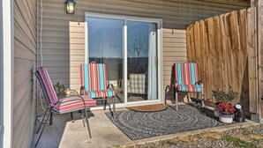A covered patio with two striped chairs, a small table, and a potted plant. - Sunny Family-friendly Branson Home! (Branson)