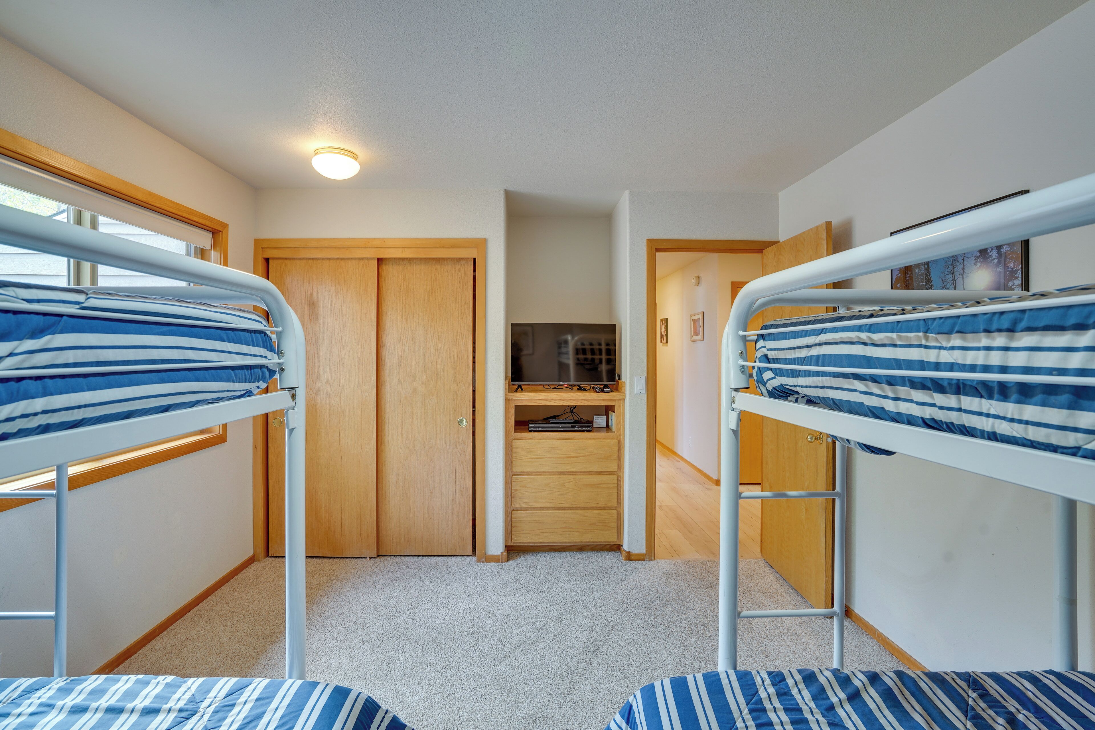 Habitación compacta con literas, una puerta de madera y una pequeña zona de kitchenette.