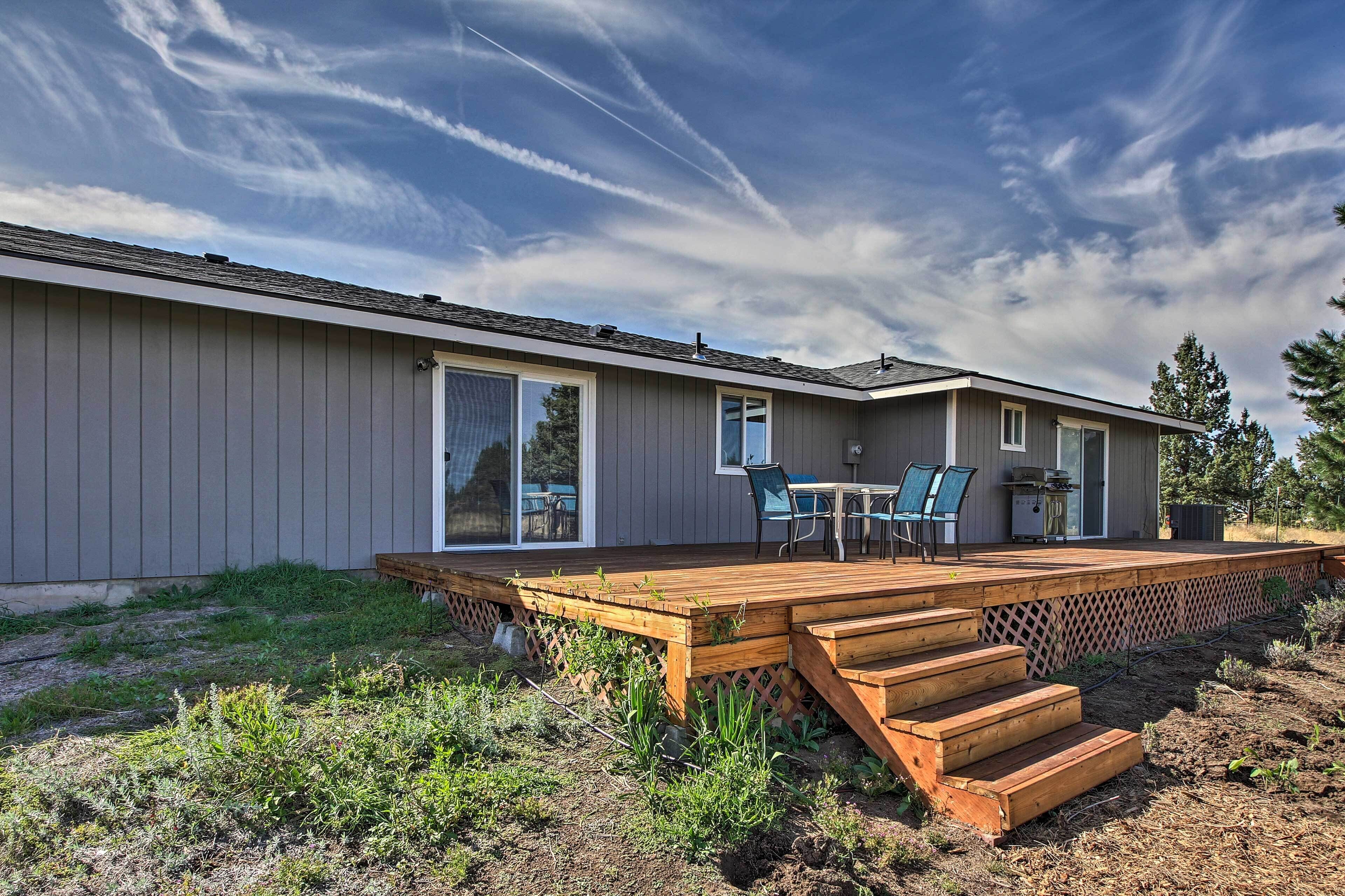 A modern house with a deck, a patio with outdoor furniture, and a large window.