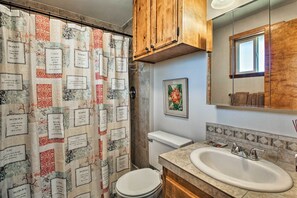 Een badkamer met douchegordijn met inspirerende citaten, een toilet, een wastafel en een spiegel.