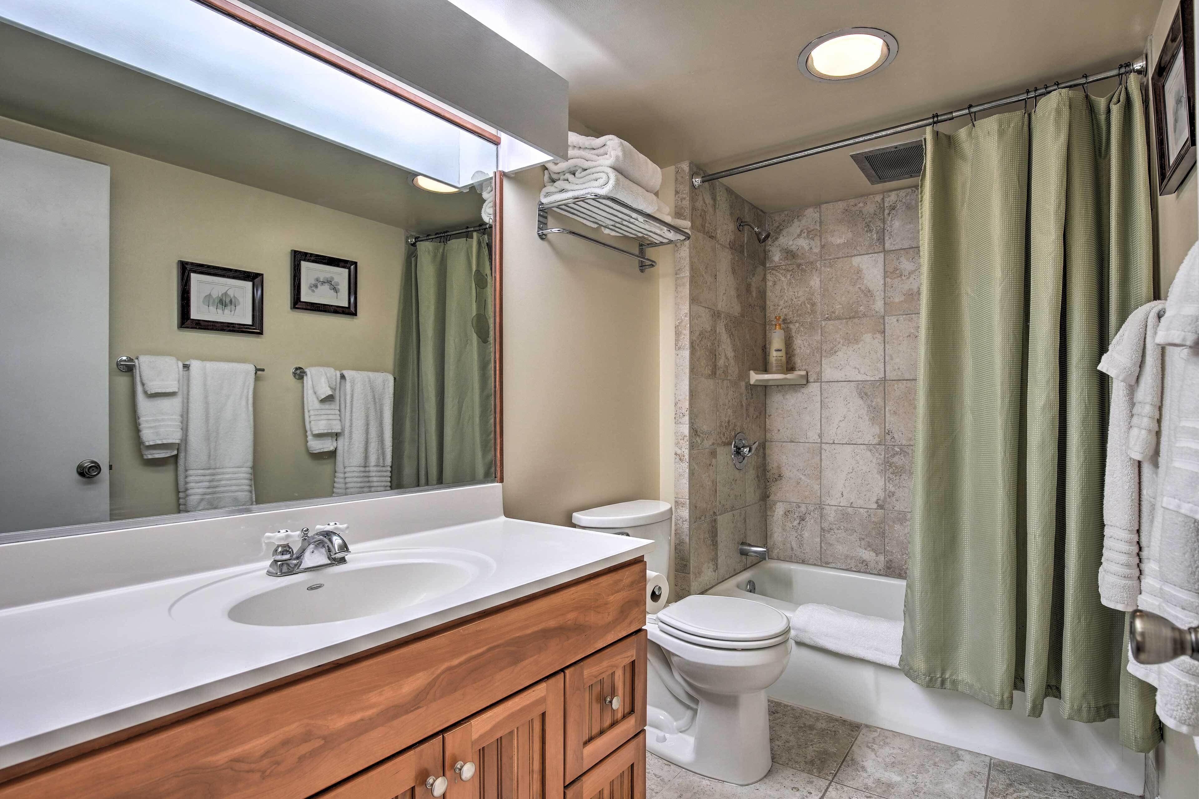 A bathroom with a sink, mirror, toilet, and shower.