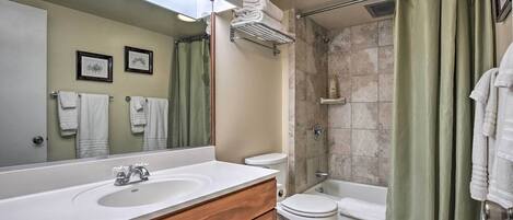 A bathroom with a sink, mirror, toilet, and shower.