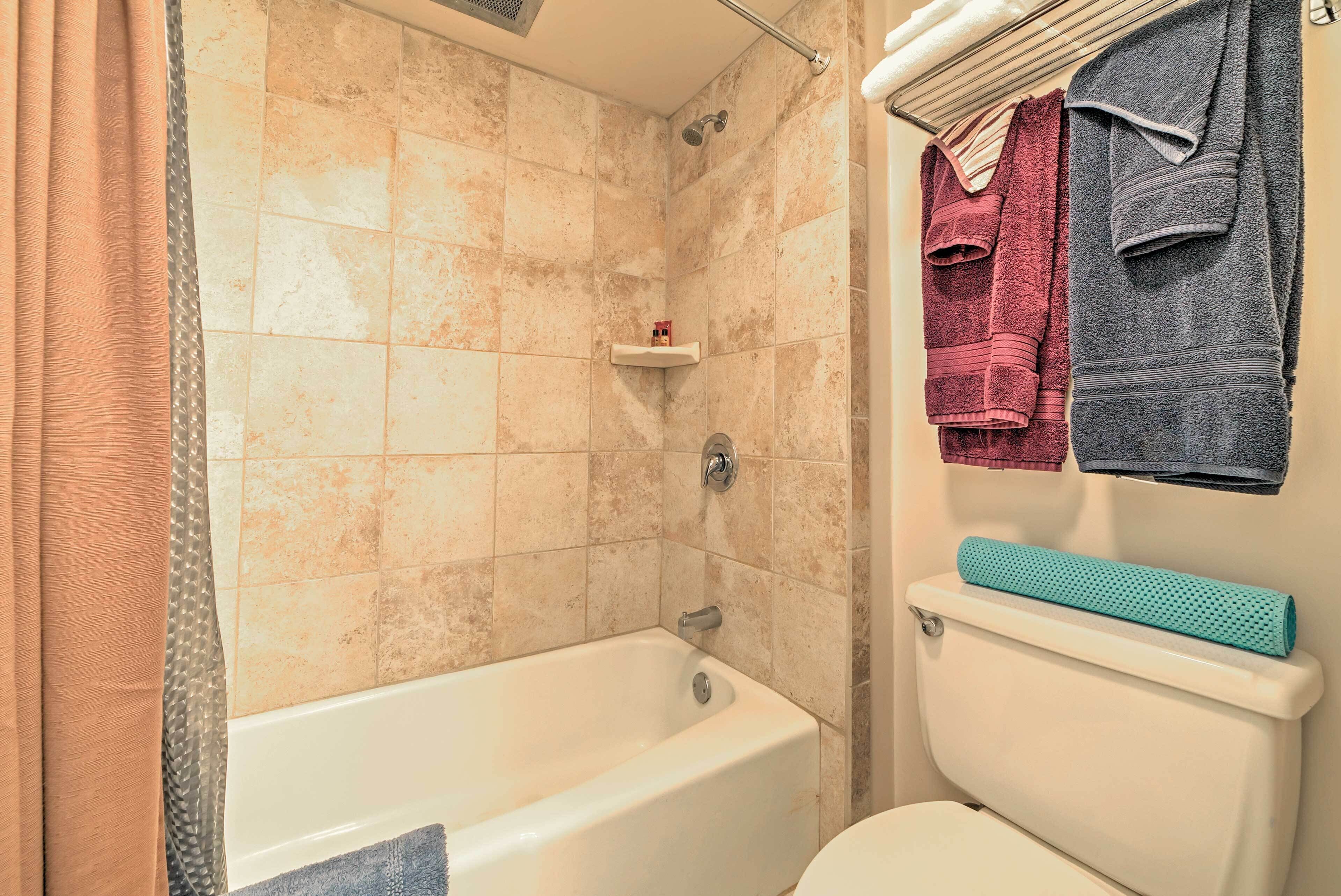 A bathroom with a bathtub, a toilet, and a towel rack with towels.