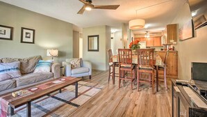 A living room with a sofa, a coffee table, and a dining area with a table and chairs. - Kailua-kona Condo w/ 2 Private Lanais! (Kailua-Kona)