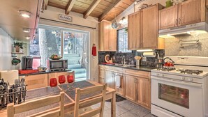 Une cuisine dotée de meubles en bois, d’une cuisinière à gaz, d’un four à micro-ondes et d’un coin repas avec une table et des chaises.