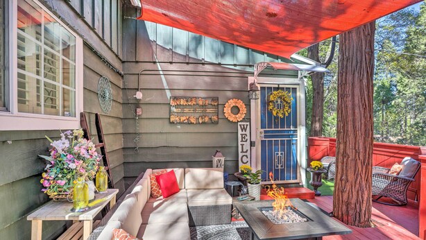 Une terrasse extérieure accueillante, avec un canapé, un foyer et un fauteuil en osier.