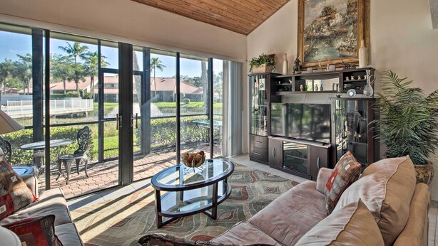 A spacious living room with a large glass door leading to a patio, a comfortable sofa, a coffee table, and a painting on the wall.