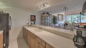 A kitchen with a large island, a refrigerator, a coffee maker, and a cabinet with glass doors.