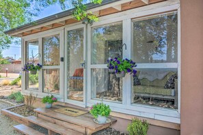 Un porche abrité avec un banc, des plantes en pot et une porte en bois.