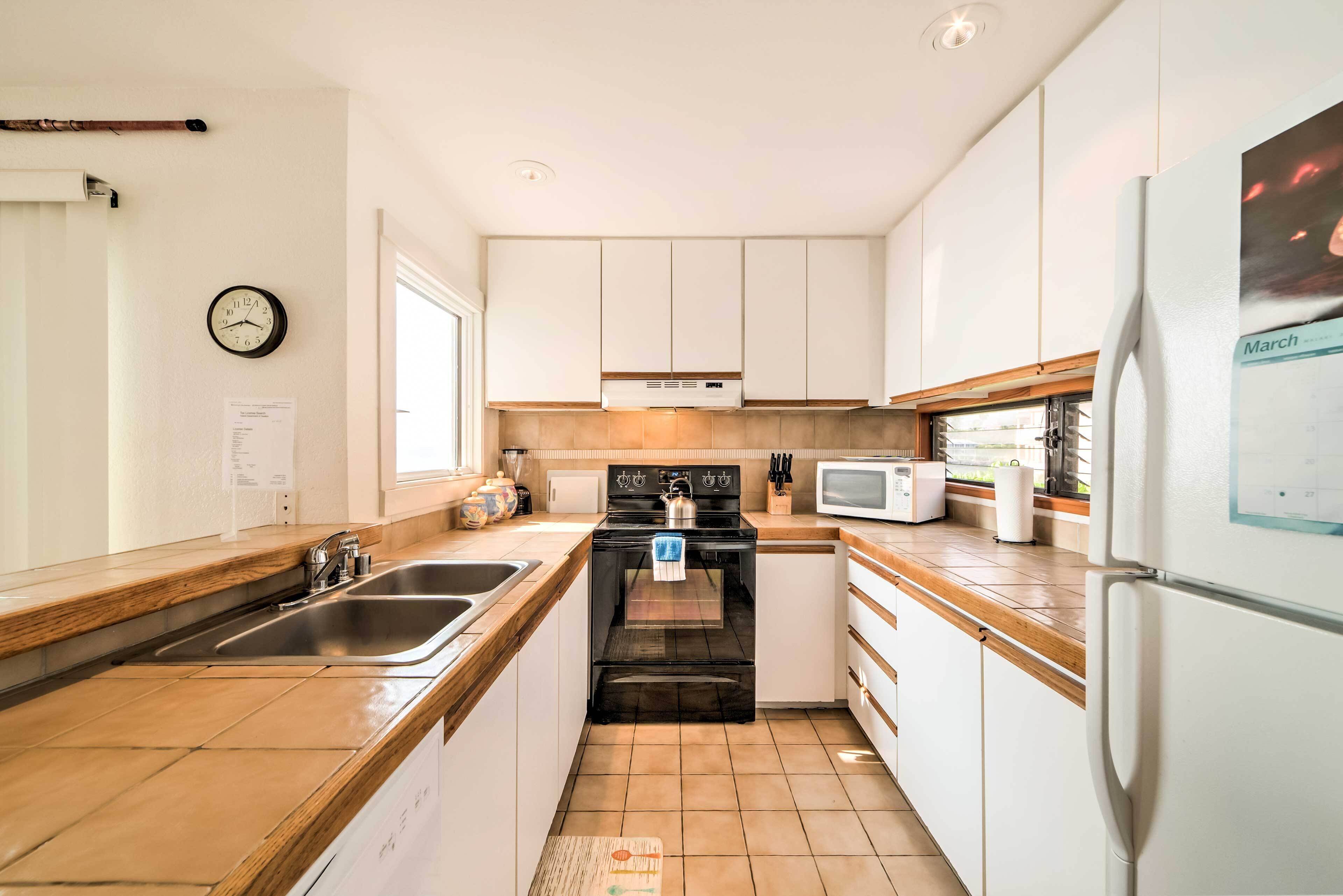 Una cocina moderna con armarios blancos, una estufa negra, un microondas y un refrigerador.