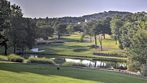 A golf course with a pond, trees, and a distant building. - 5 Mi to Dtwn & Strip! Branson Condo w/ Indoor Pool (Branson)