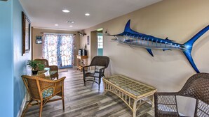 Ein Zimmer mit Korbmöbeln, einem großen Wandbild mit Fischen und Blick ins Freie.