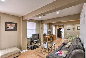 A living room with a glass coffee table, a leather couch, a TV on a stand, and a dining area with a table and chairs. - Private Dock, Views: Waterfront Rockport Home! (Rockport)