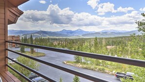 A balcony with a view of a mountain range, a parking area, and a building with a red roof. - Resort Perks & Trail Access: Silverthorne Condo! (Silverthorne)