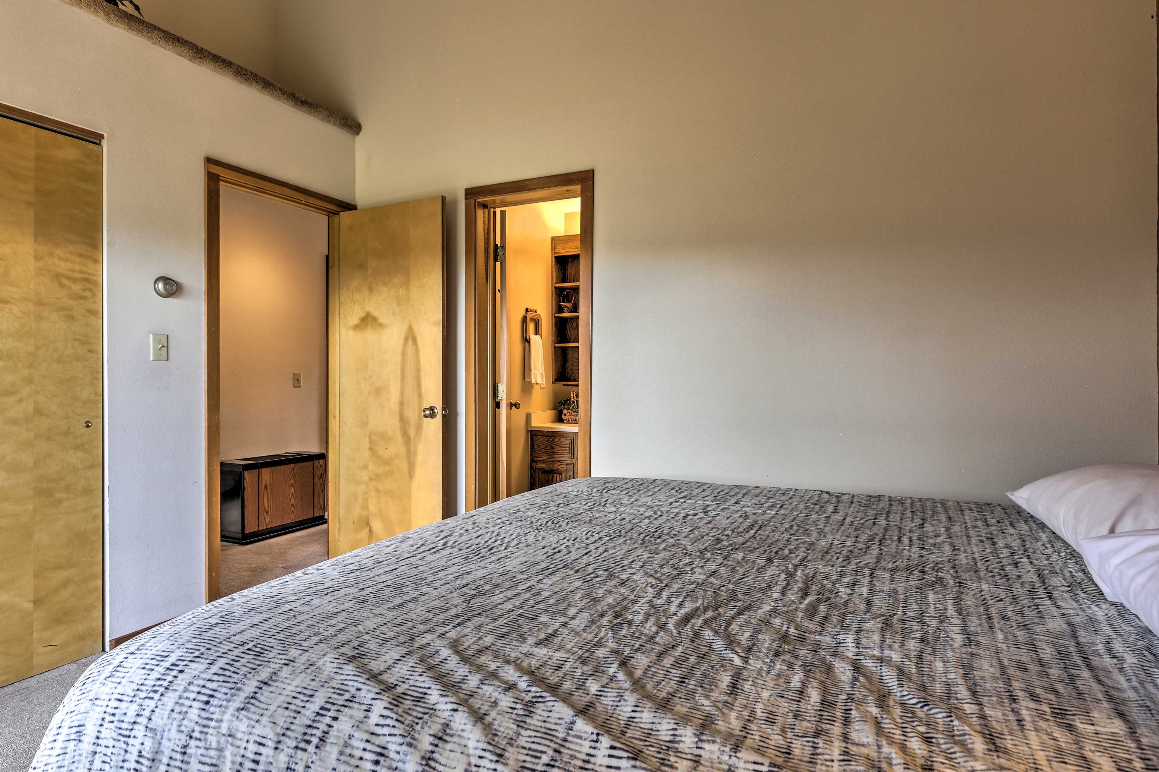 Un dormitorio con cama, armario y puerta abierta hacia un baño.