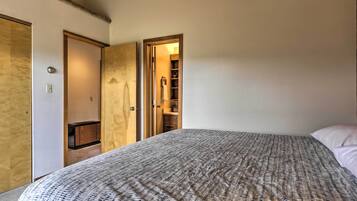 Un dormitorio con cama, armario y puerta abierta hacia un baño.