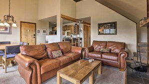 A spacious living room with two brown leather sofas, a wooden coffee table, and a dining area with a wooden table and chairs. - Resort Perks & Trail Access: Silverthorne Condo! (Silverthorne)