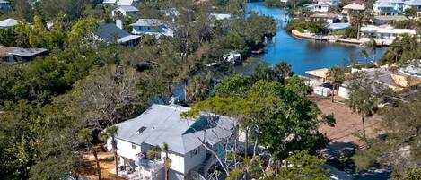 Un quartier résidentiel avec des maisons, un plan d’eau et une grande maison blanche dotée d’un balcon.