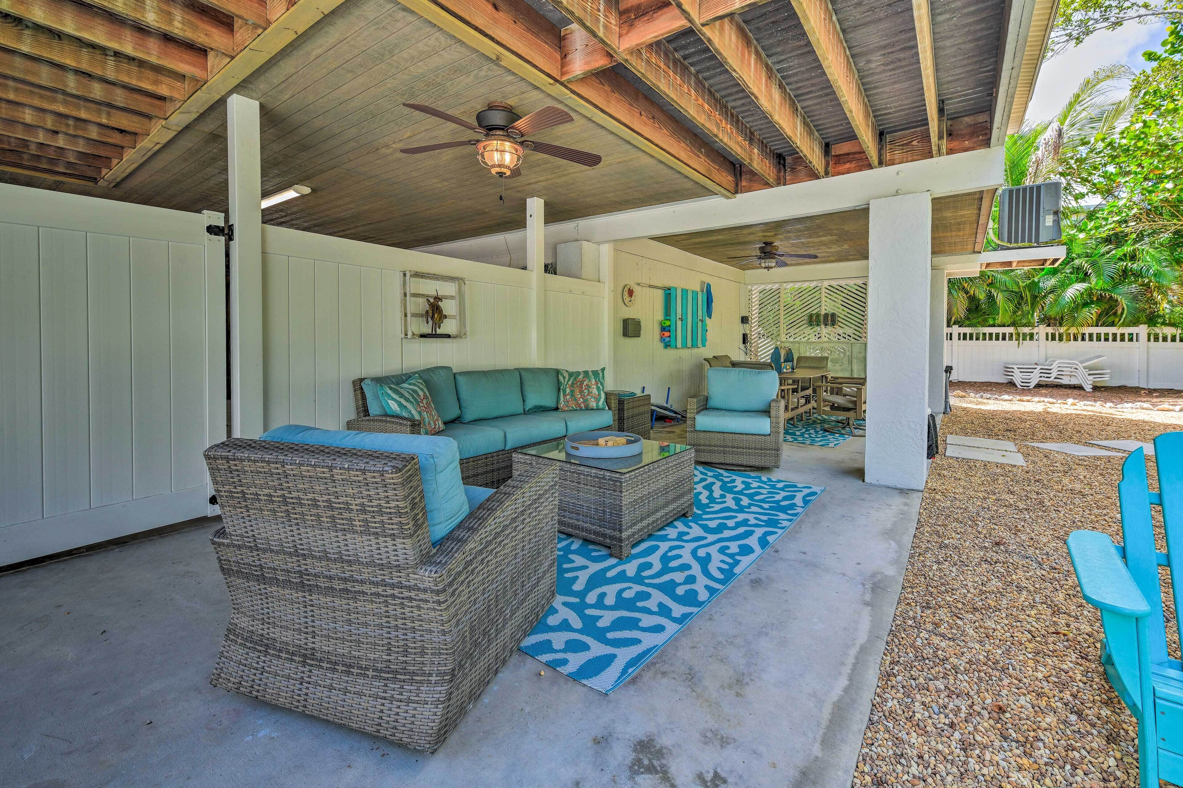 A covered outdoor seating area with wicker furniture and a blue patterned rug.