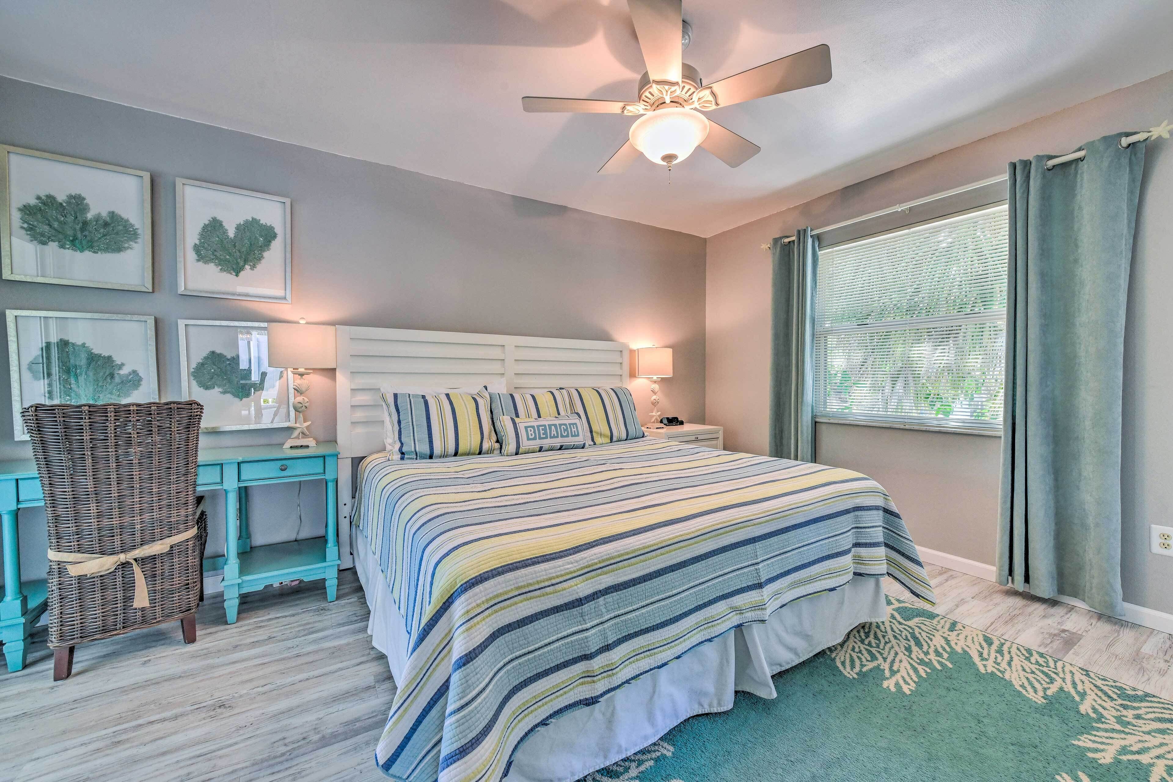 A bedroom with a bed, a desk, a chair, and a ceiling fan.