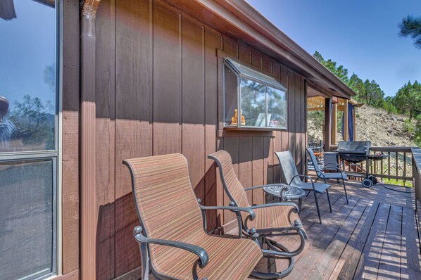 A wooden deck with outdoor furniture, a grill, and a view of a natural landscape. - Tranquil Ruidoso Cabin w/ Private Hot Tub! (Ruidoso)
