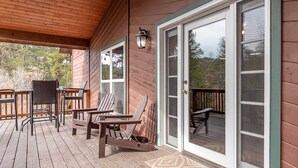A wooden deck with outdoor seating, a sliding glass door, and a lantern. - Stunning Ruidoso Cabin w/ Private Hot Tub! (Ruidoso)