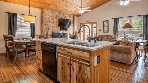 A spacious kitchen with wooden cabinets, a central island, and a dining area with chairs. - Stunning Ruidoso Cabin w/ Private Hot Tub! (Ruidoso)