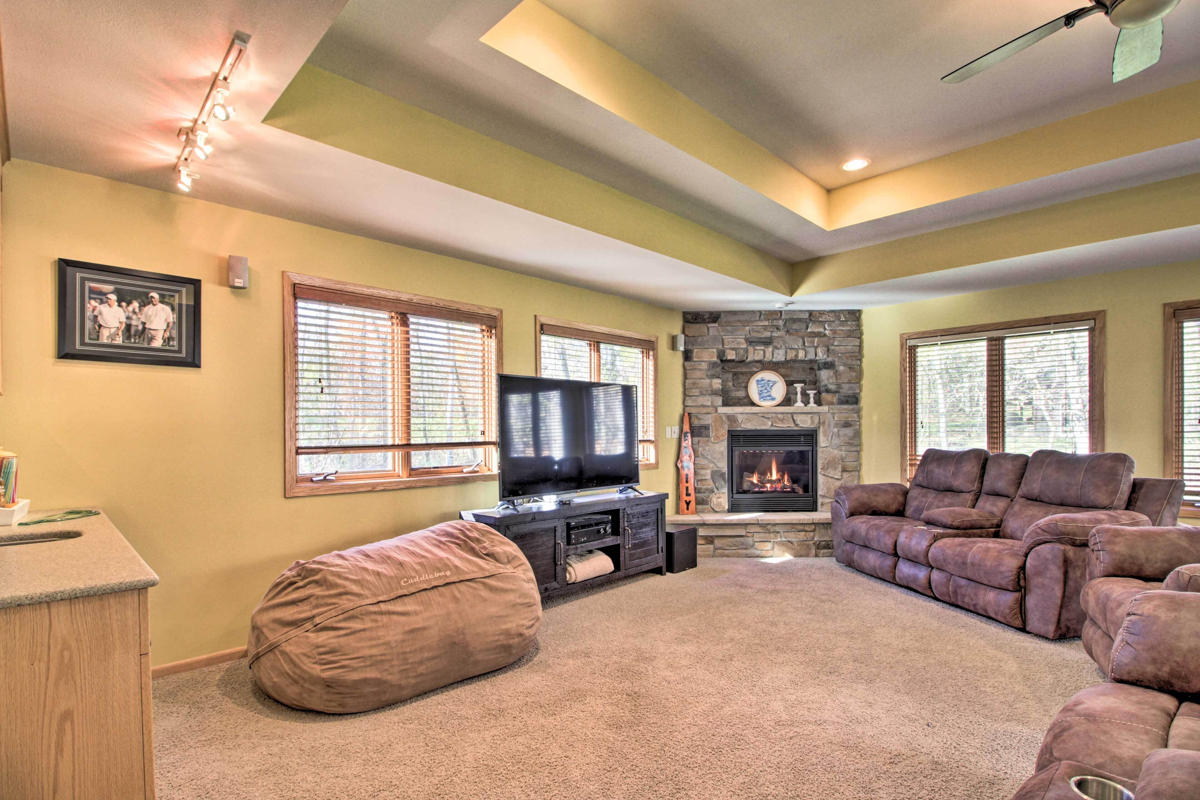 A living room with a stone fireplace, a television, a beige bean bag, and a brown sectional sofa.