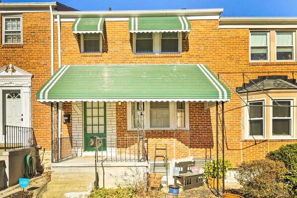 Una casa de ladrillo de dos pisos con un toldo verde y una puerta principal.