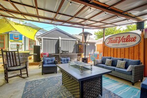 An outdoor patio area with a covered seating area, a grill, and a sign for True Value Hardware Stores. - San Antonio Tiny Home, 4 Mi to Brackenridge Park (San Antonio)
