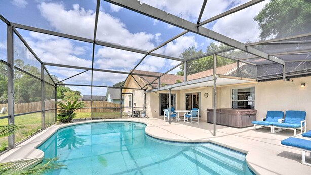 Une piscine extérieure couverte avec un espace patio, des chaises longues et un jacuzzi.