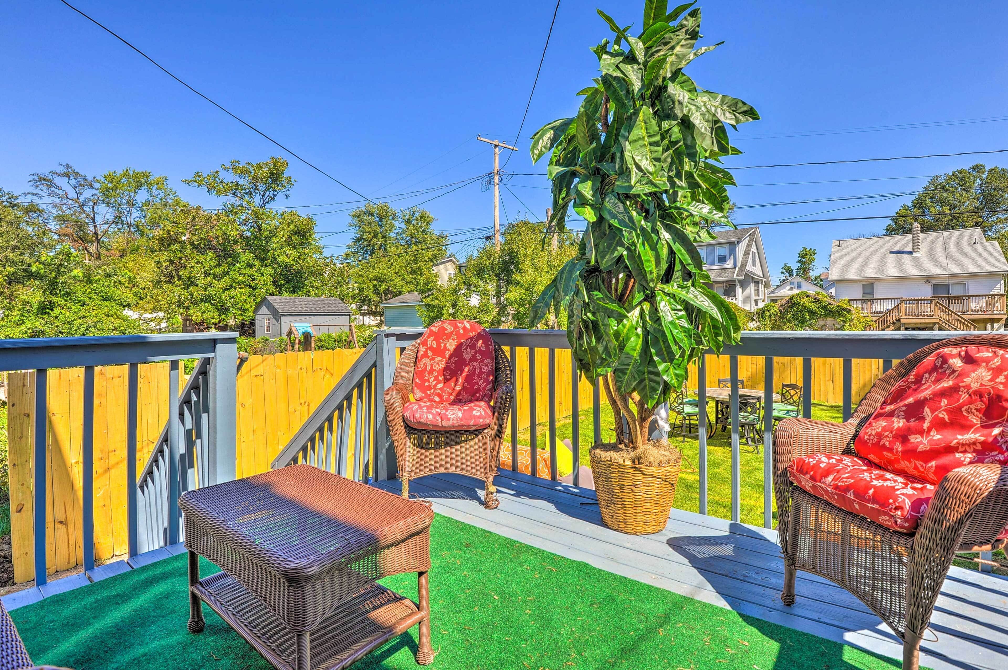 A wooden deck with wicker furniture and a potted plant.