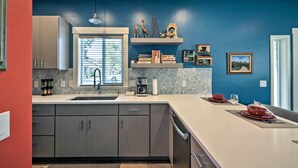 A modern kitchen with a large island, grey cabinets, and a blue accent wall. - Missoula Getaway w/ Balcony, 2 Mi to Downtown! (Missoula)