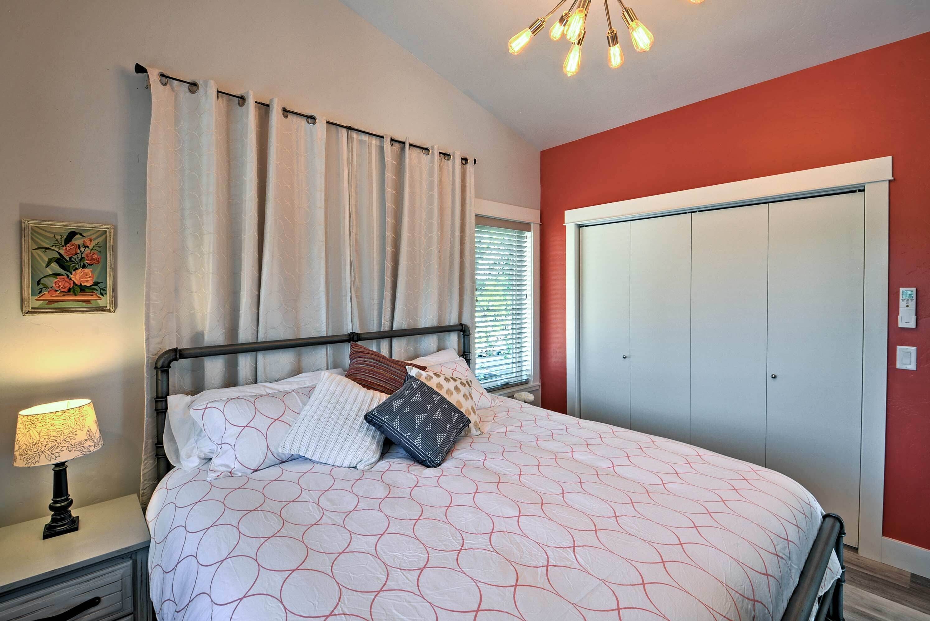 A bedroom with a bed, nightstand, lamp, curtains, window, and wardrobe.