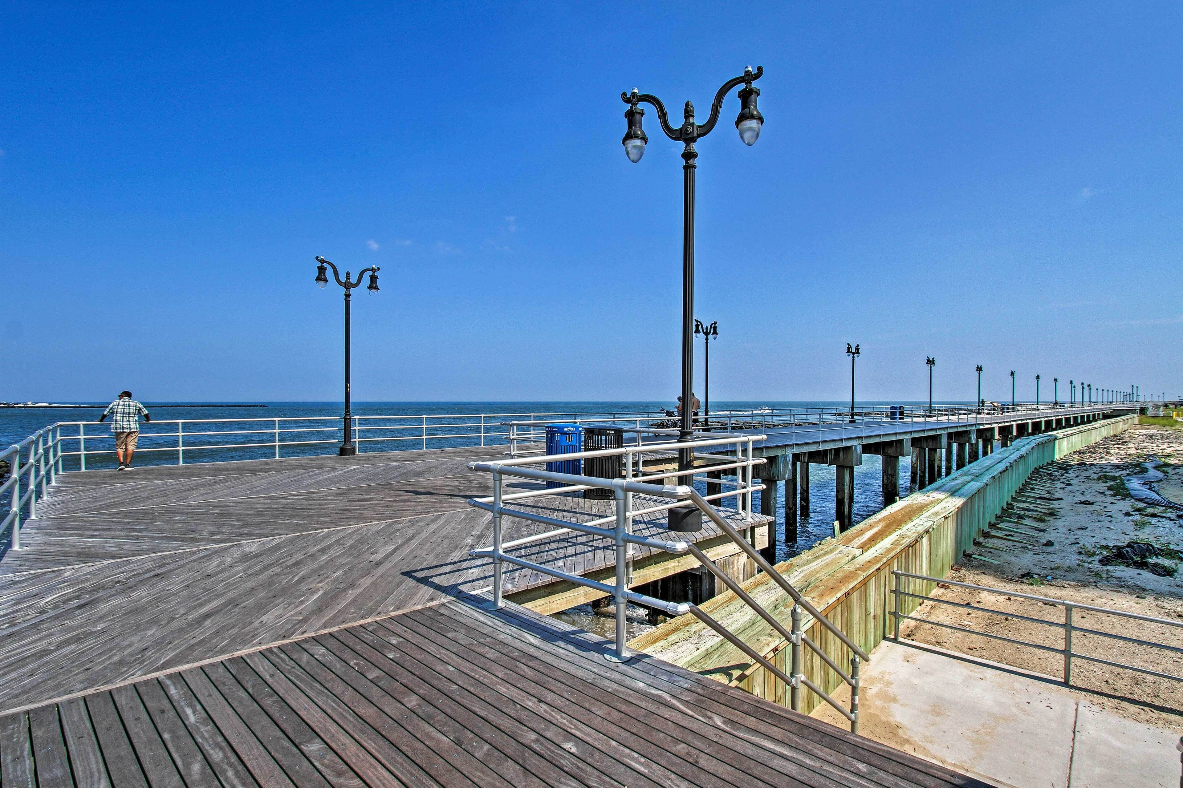A wooden pier extending into the water with railings and street lamps.