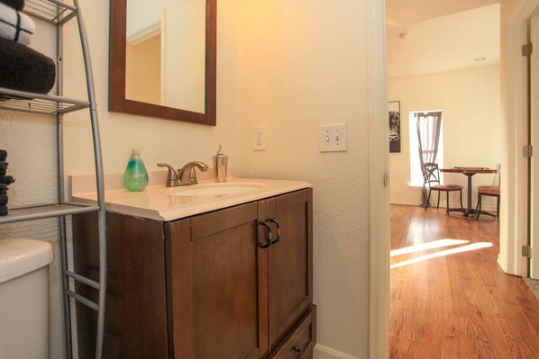 A bathroom with a wooden vanity, a mirror, and a shelf with towels. - Downtown Home w/ Grill: 5 Mi to Garden of the Gods (Colorado Springs)