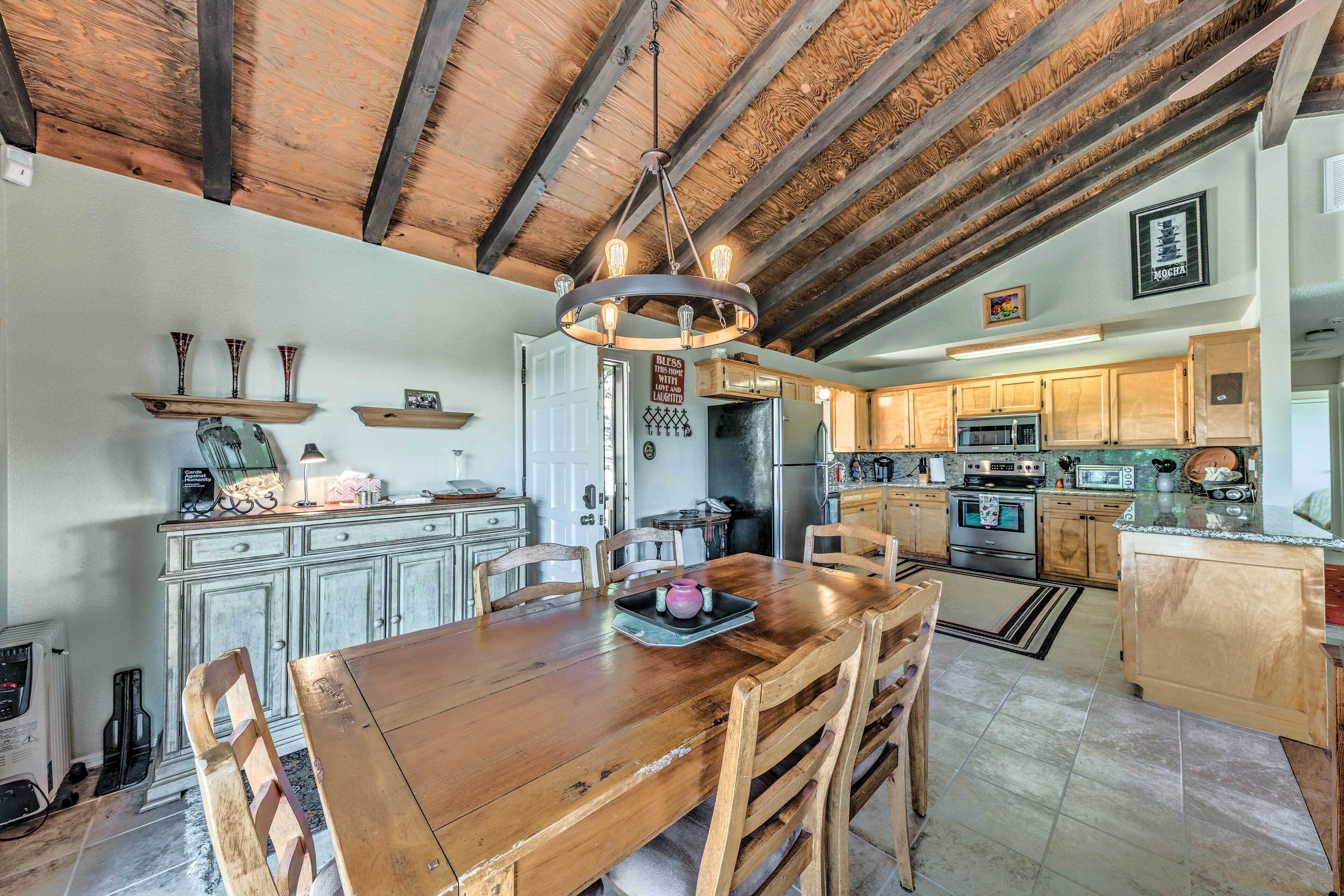 Een ruime keuken met houten balken, een houten eettafel en moderne apparatuur.