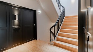 Un intérieur moderne avec un escalier, des portes noires et un plancher en bois.