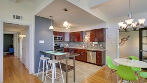 A modern kitchen with stainless steel appliances, a central island, and bright green chairs. - Bright & Modern Texas Getaway - 7 Mi to The Alamo! (San Antonio)