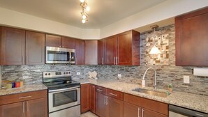 A modern kitchen with wooden cabinets, stainless steel appliances, and a tiled backsplash. - Bright & Modern Texas Getaway - 7 Mi to The Alamo! (San Antonio)