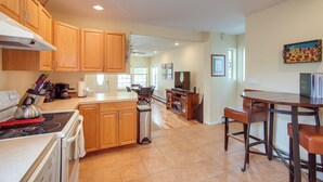 A kitchen with wooden cabinets, a stove, a sink, and a dining area with a bar stool. - Buena Vista 'shambala' Sanctuary Near Main St! (Buena Vista)