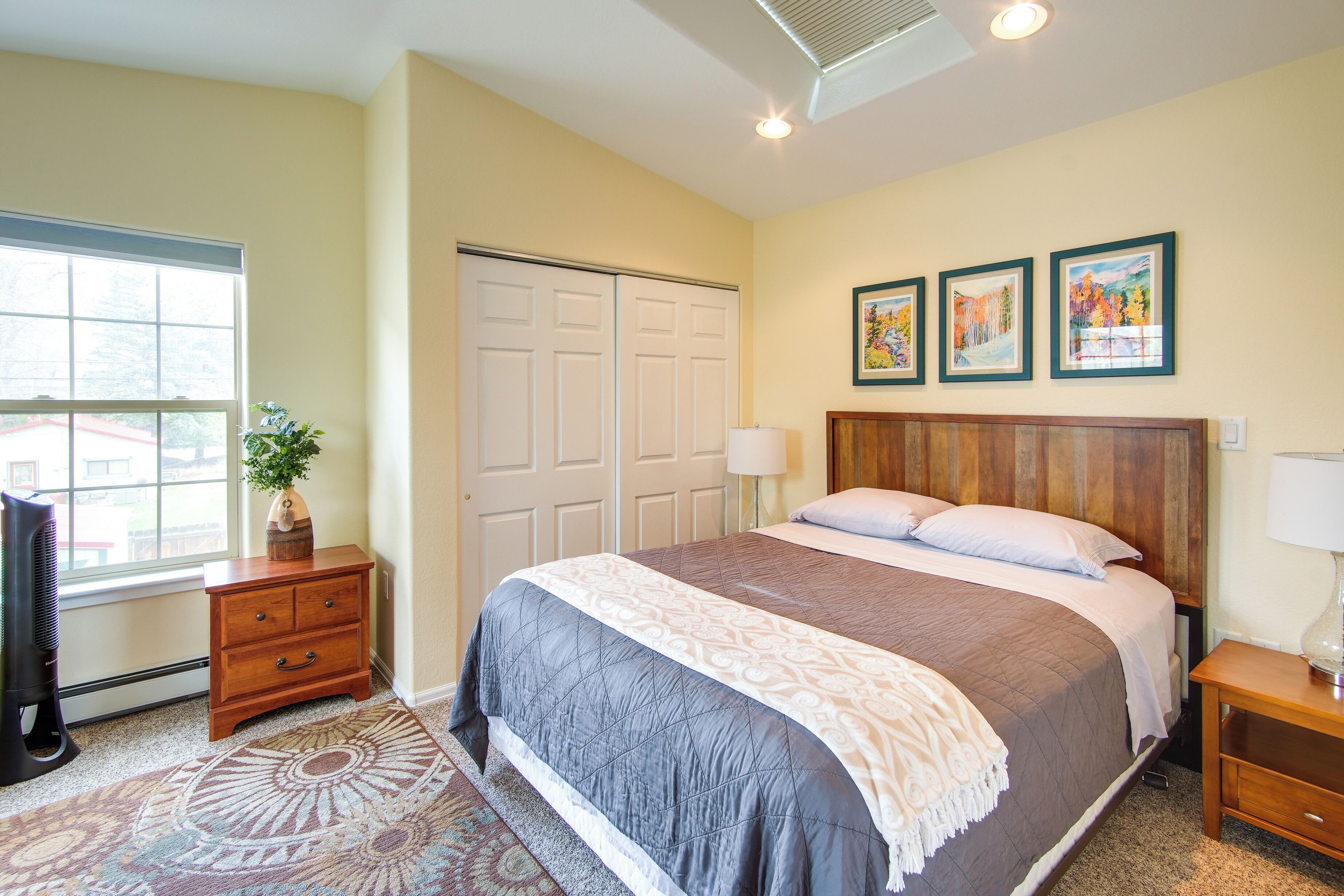A bedroom with a bed, a dresser, a lamp, and a window.