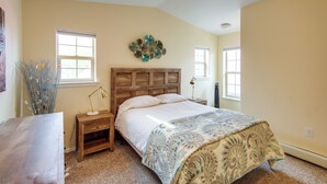 A bedroom with a wooden headboard, a large bed with a patterned bedspread, two bedside tables with lamps, and a vase with dried plants. - Buena Vista 'shambala' Sanctuary Near Main St! (Buena Vista)