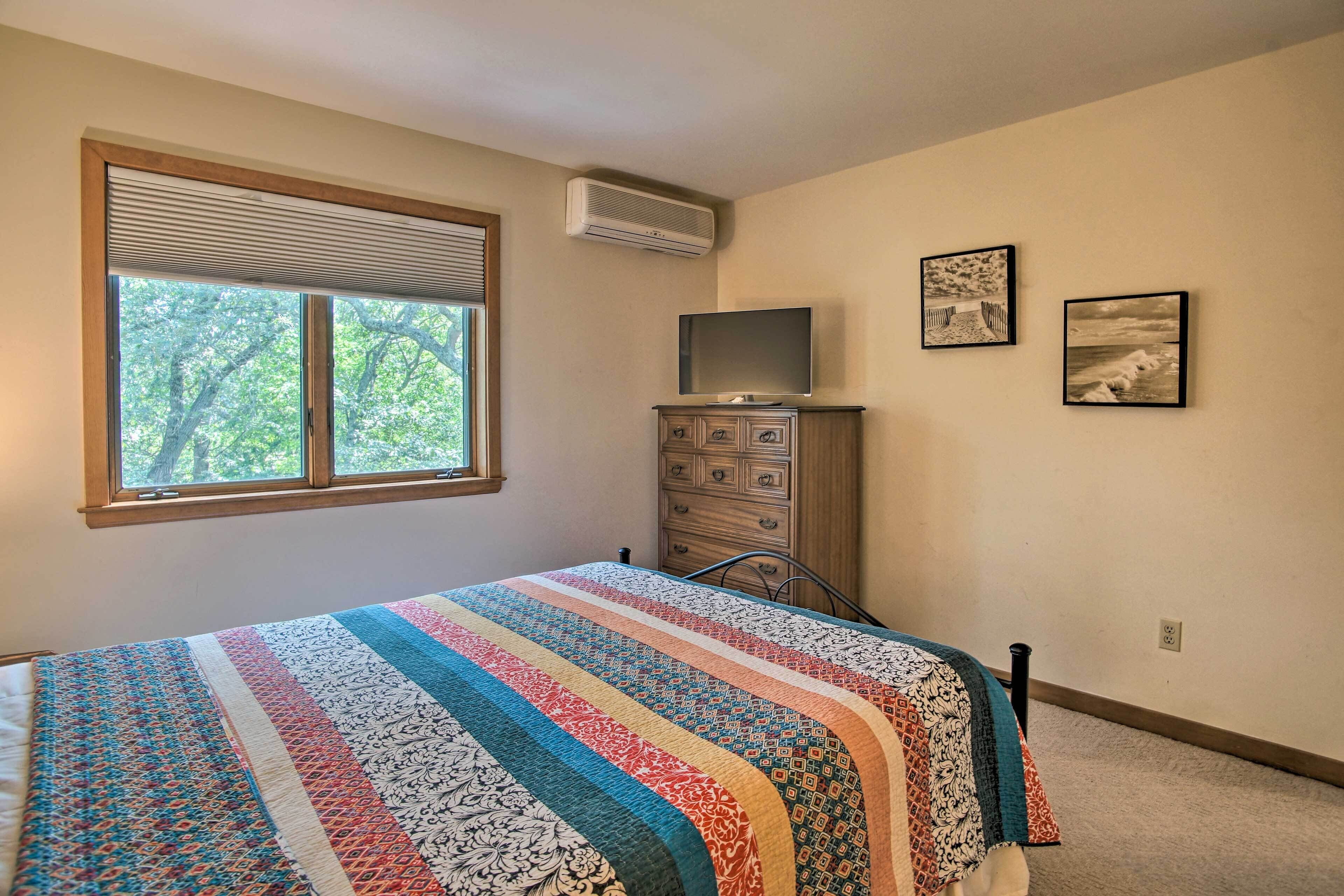Une chambre à coucher comprenant un lit, une commode, un téléviseur et deux tableaux encadrés accrochés au mur.