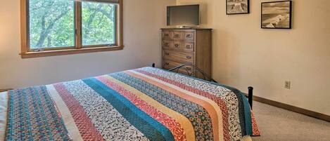 Une chambre à coucher comprenant un lit, une commode, un téléviseur et deux tableaux encadrés accrochés au mur.