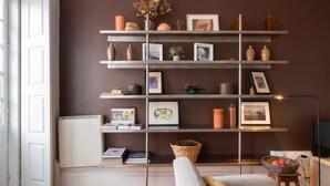 A living room with a bookshelf filled with books, decorative items, and framed pictures.