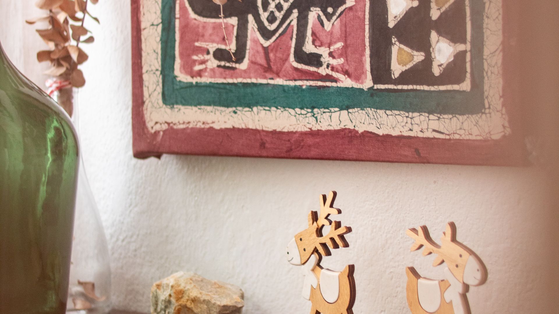 A wall with a framed artwork and wooden cutouts of reindeer.