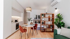 Ein moderner, kompakter Wohnraum mit Essbereich, Küchenzeile und einem grünen Sofa.