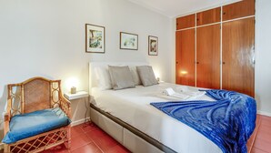 Une chambre à coucher comprenant un lit, une table de chevet, une chaise et une armoire.