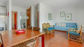 Un salon moderne avec une table à manger en bois, un canapé bleu et des chaises en osier.